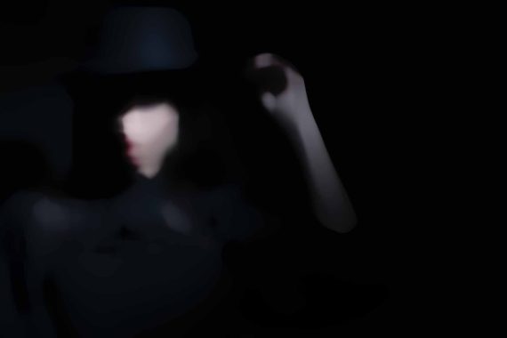 Woman wearing a black hat on a dark backdrop
